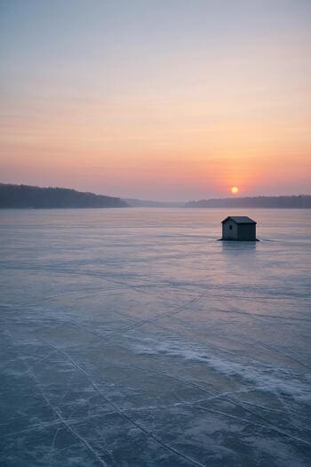 Wide view of a quiet winter lake at dawn near the end of the season.