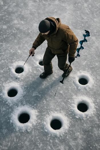 Close view of a gloved hand checking the edge of an ice hole.